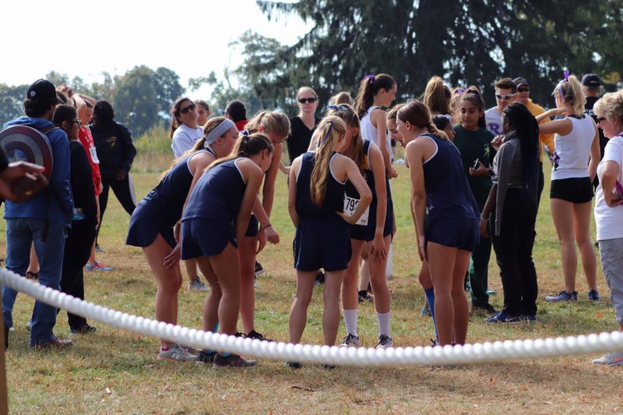Del Val’s girls’ cross country team huddles up at the start line before a race.  