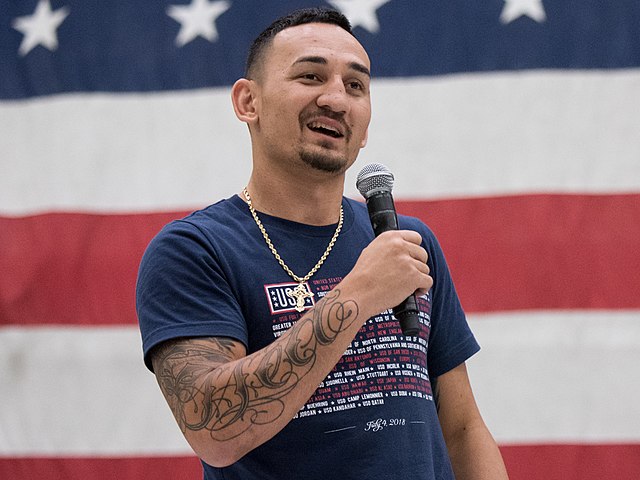 UFC Featherweight Champion Max Blessed Holloway answers questions during a show for troops at Bagram Air Field, Afghanistan; the fifth stop on the annual Vice Chairman’s USO Tour, April 26, 2018. Comedian Jon Stewart, country music artist Craig Morgan, celebrity chef Robert Irvine, professional fighters Max “Blessed” Holloway and Paige VanZant, and NBA Legend Richard “Rip” Hamilton will join Gen. Selva on a tour across the world as they visit service members overseas to thank them for their service and sacrifice. (DoD Photo by U.S. Army Sgt. James K. McCann)