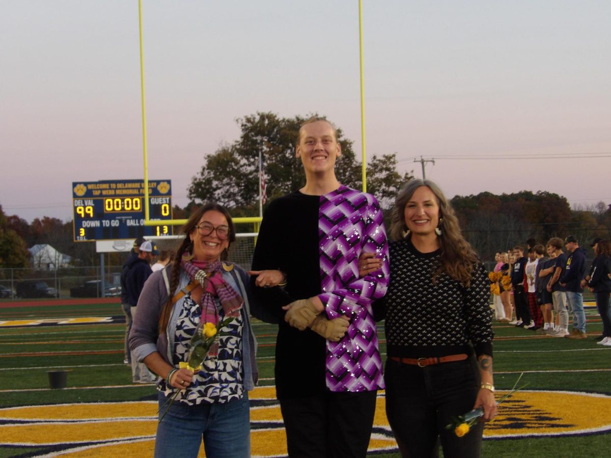 Cayden Puttlitz, a leader of the color guard, with his parents on Senior Night.