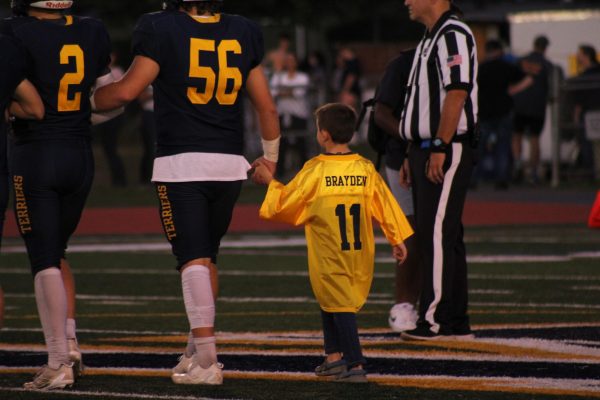 Brayden Bond being walked out onto the field during Youth Night at a Del Val football game. The stands all gave their support and posters were made saying "Brave Like Brayden."