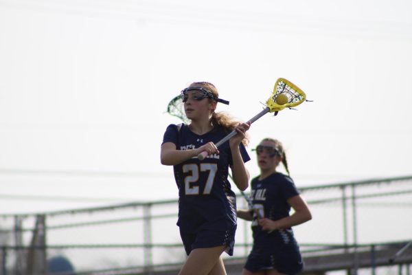 Sophomore Lacey Theesfeld holding the lacrosse ball about to pass it. Theesfeld played in the game against Somerville on March 31 where the Terriers won 14-12.