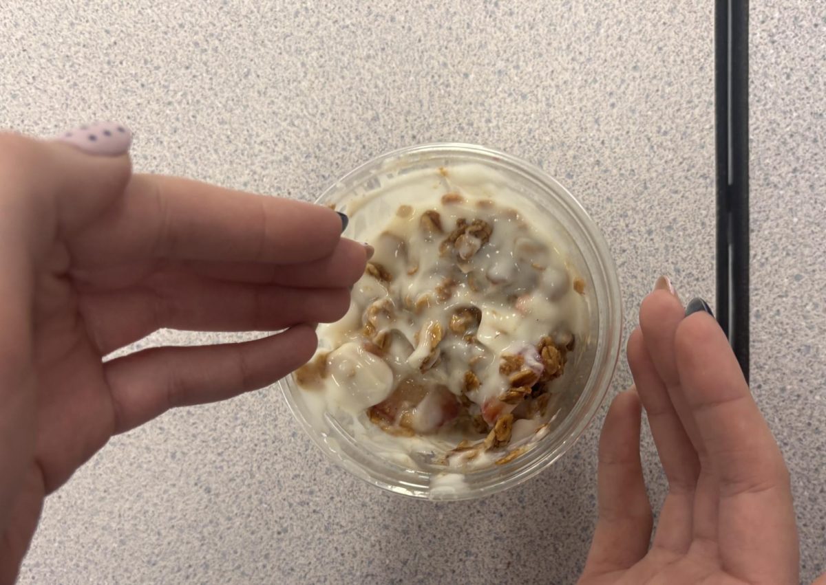 Student going hands first into their yogurt during lunch. The new silverware ban grants students the ability to challenge themselves by eating without a spoon. 