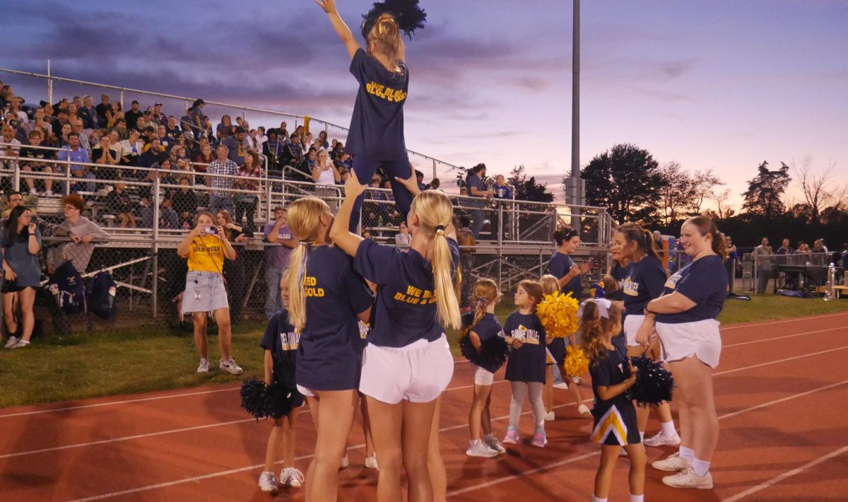 Varsity cheerleaders lift a future Terrier at the Del Val v. Voorhees varisty football game. The cheerleaders host several youth events throughout the year, including Youth Night each fall.