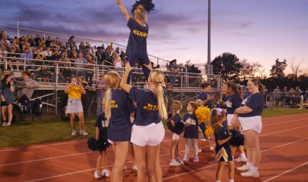 Varsity cheerleaders lift a future Terrier at the Del Val v. Voorhees varisty football game. The cheerleaders host several youth events throughout the year, including Youth Night each fall.