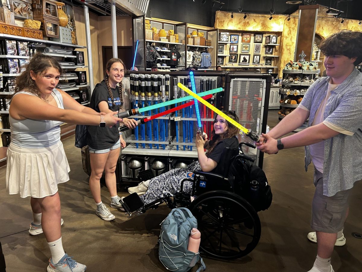 Kate Giles, Natalie Petronko, Avery Matlee and Ryan Carr pose in the Star Wars gift shop after going on Star Tours. As the thrilling ride ended, they excitedly picked up their lightsabers.