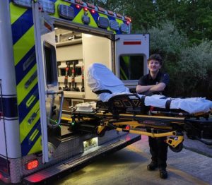 Del Val graduate Joseph Oliveras stands with a gurney outside of an ambulance. Oliveras was apart of the EMT training program when he attended Del Val. He graduated in 2026.
