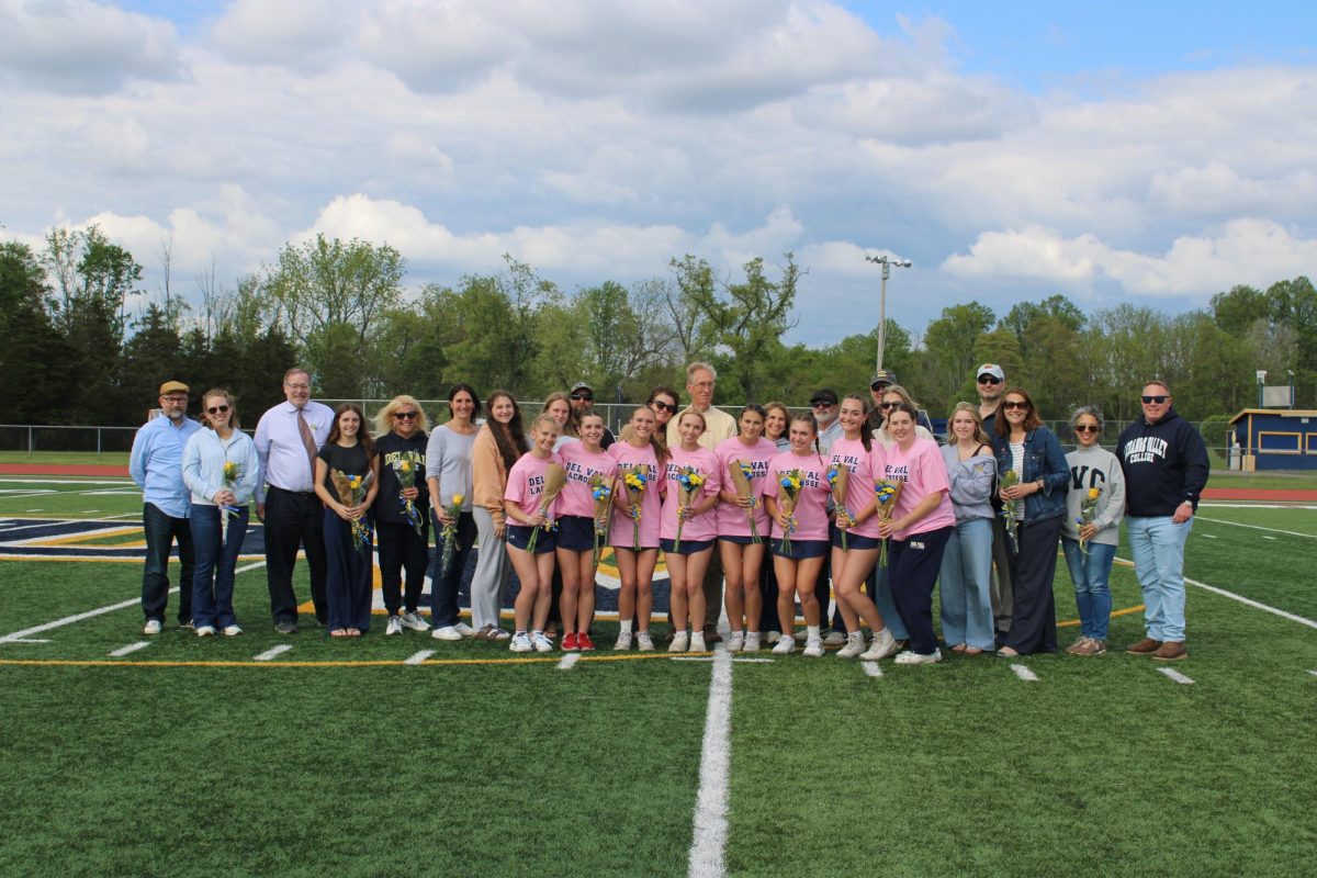 The girls lacrosse seniors and family members stand together for a photo. They are sharing a heartwarming moment before their game.