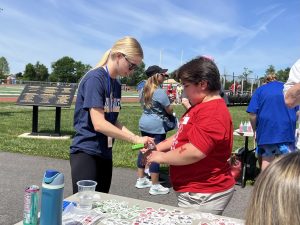 Jenna Sedlacek tattoos a Holland Township School student. Tournament of Champions had a variety of stations, including temporary tattoos, sprinting, javelin, sand art and long jump.