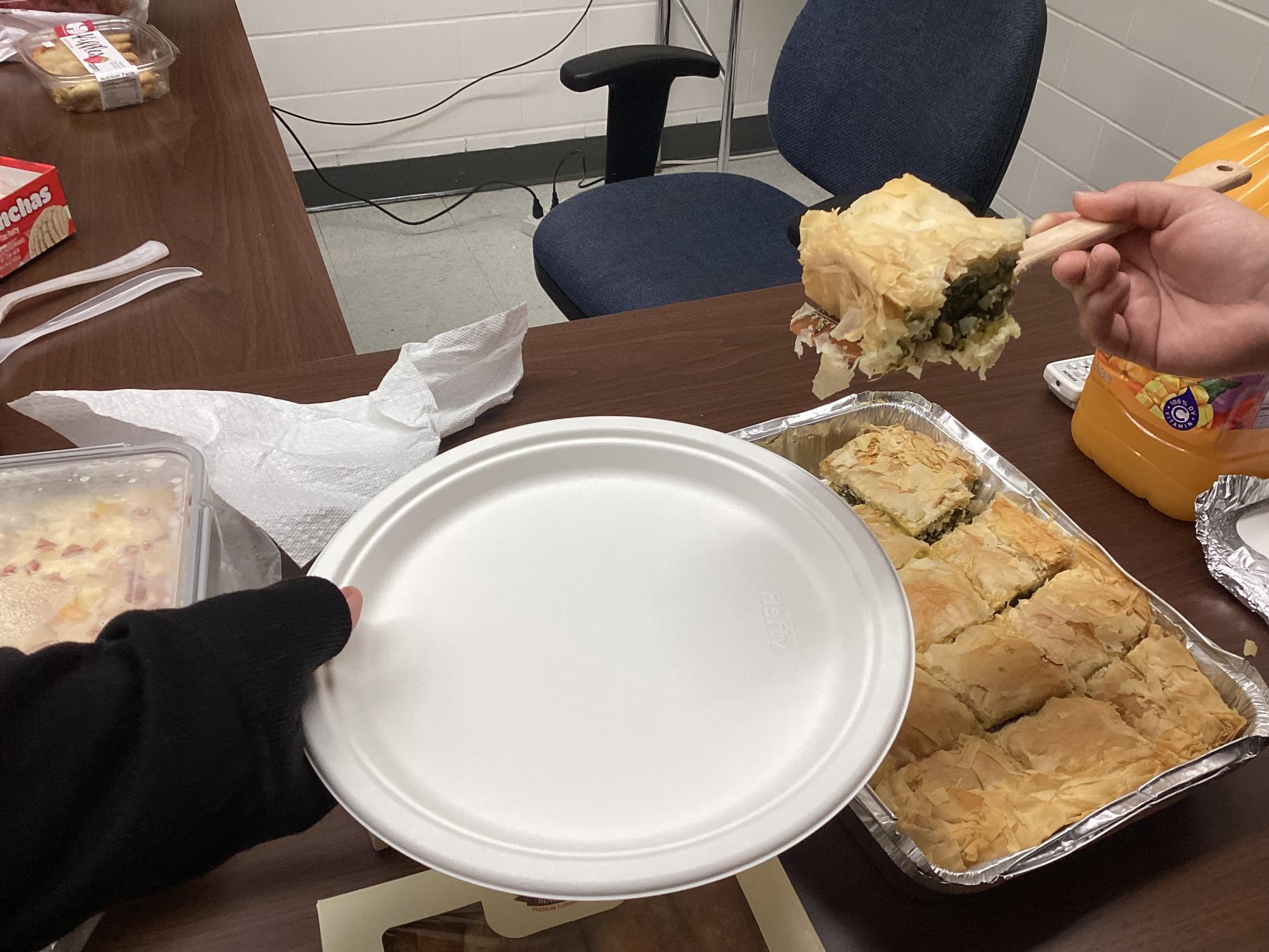 International Club member serves a traditional Greece pie, spanakopita. The dish was a favorite among the members.