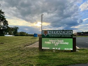 A dark cloud casts a shadow over Alexandria Township School's welcome sign. The wet weather that the clouds indicate has been considered a possible contributing factor for the fungal growth.