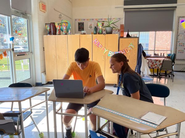 Stanton helping a student with their classwork. Stanton spent the first month of the school year building relationships with students and acting as a support for them.